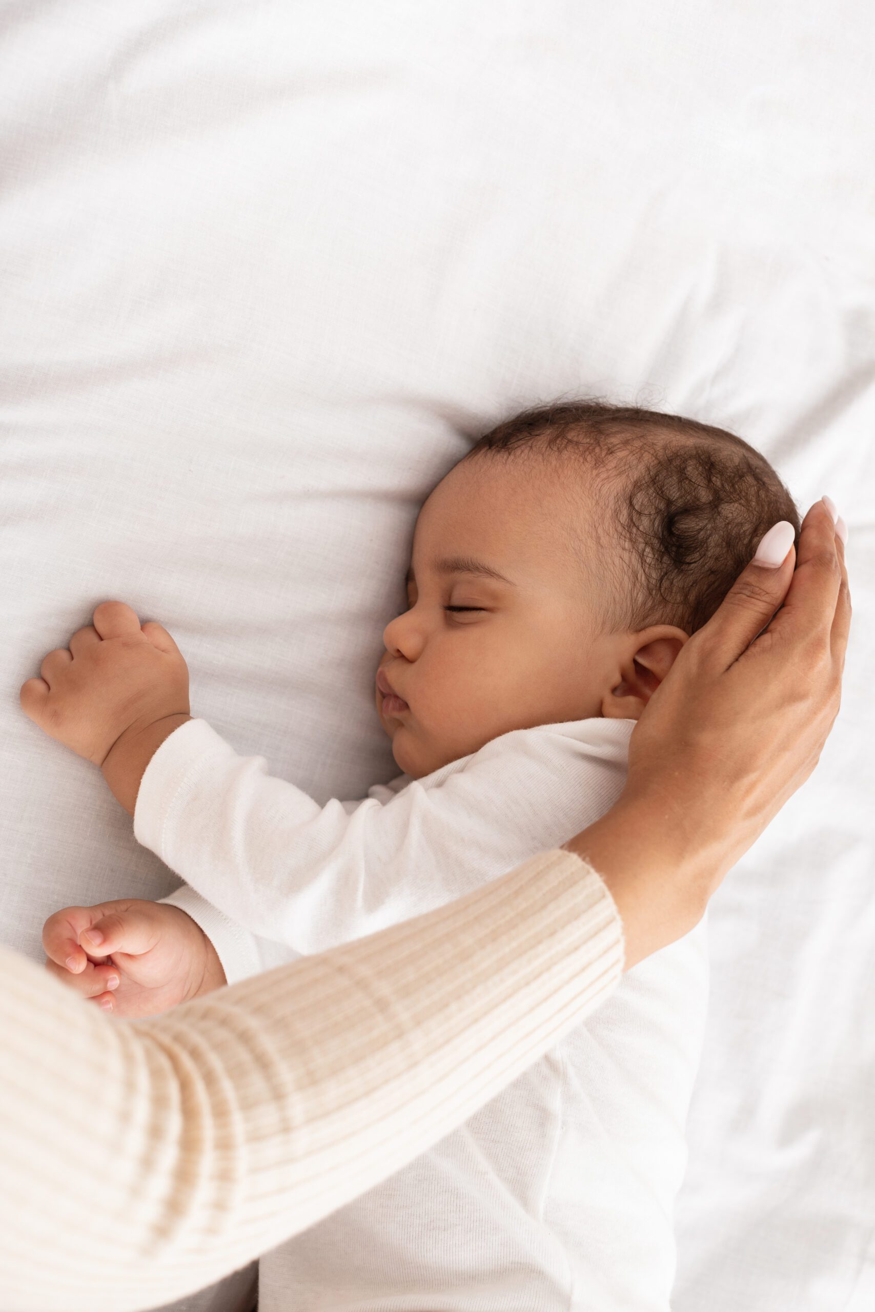 Black Mom's Hand Stroking Sleeping Baby's Head In Bed, Cropped