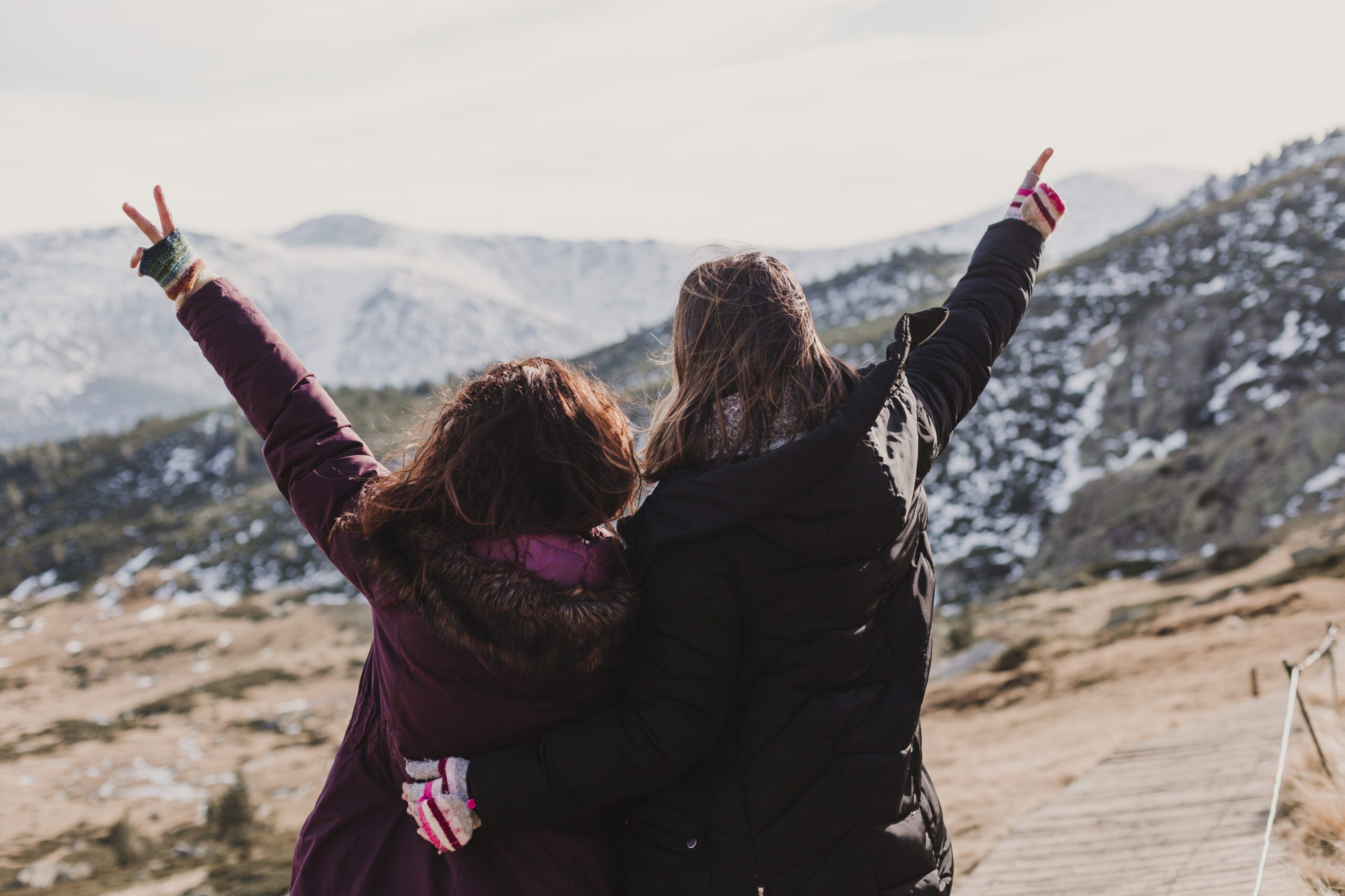 two successful hiker woman friends enjoy the view on mountain peak at sunset. happy women in nature
